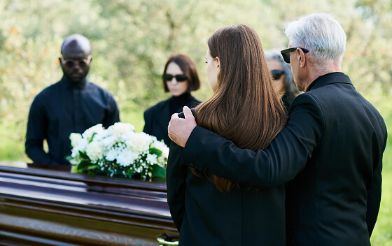 Group of people in black clothing at a funeral with a casket.