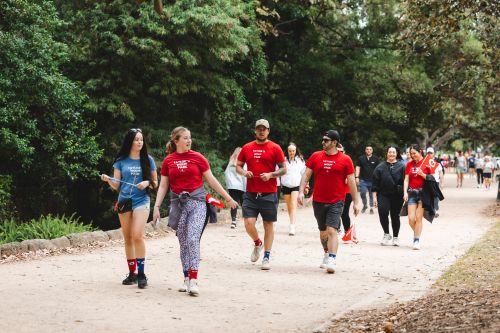 Group of people walking on a park trail with trees.